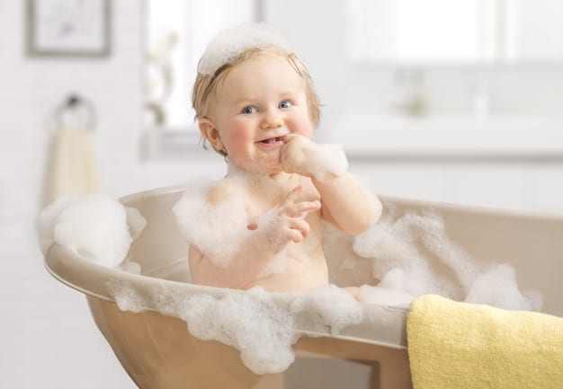 Happy laughing Infant baby toddler taking a bath playing with foam bubbles. Bathing and washing of little kid. Children care and hygiene concept.