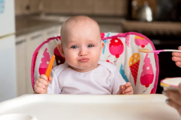 baby eats independently on a high chair