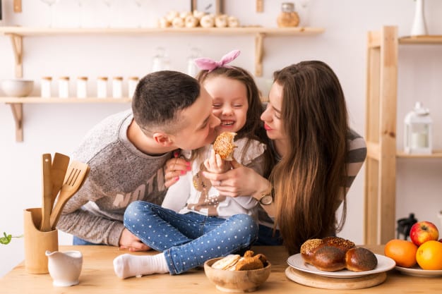 child happily eats with parents in the kitchen