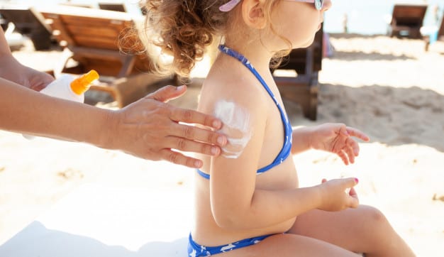 mom puts sunscreen on her daughter's shoulder