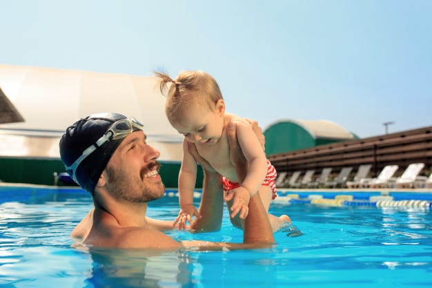 dad carrying toddler in the swimming pool