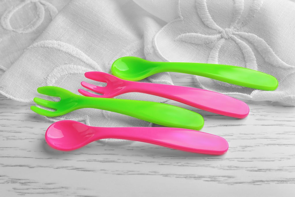 Colorful plastic eating utensils for baby on table