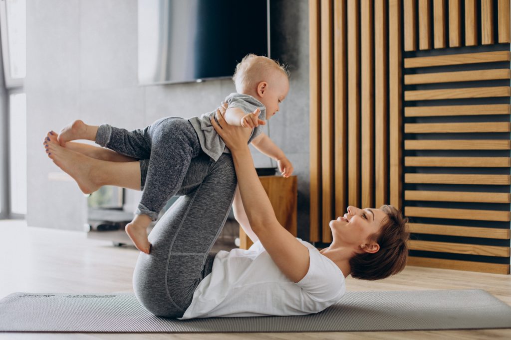Young mother practice yoga with her toddler son on mat