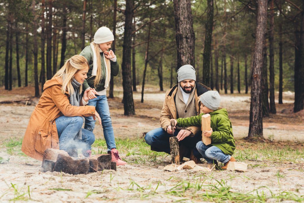 happy family making campfire while having trip on autumn day