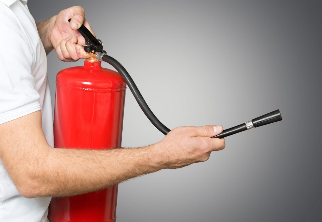 Man using fire extinguisher against grey background